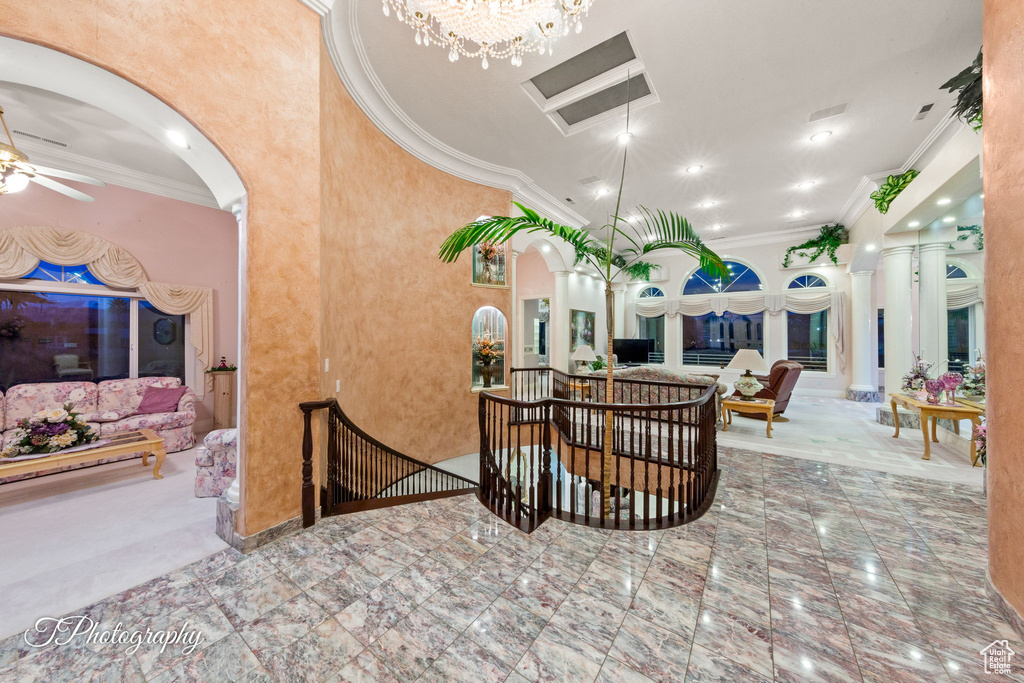 Dining room featuring arched walkways, ornamental molding, ceiling fan, baseboards, and a chandelier