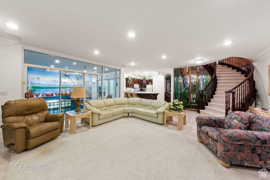 Carpeted living room with ornamental molding, stairway, and recessed lighting