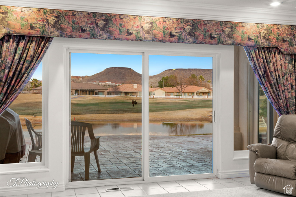 Doorway to outside with ornamental molding, a water and mountain view, and tile patterned floors