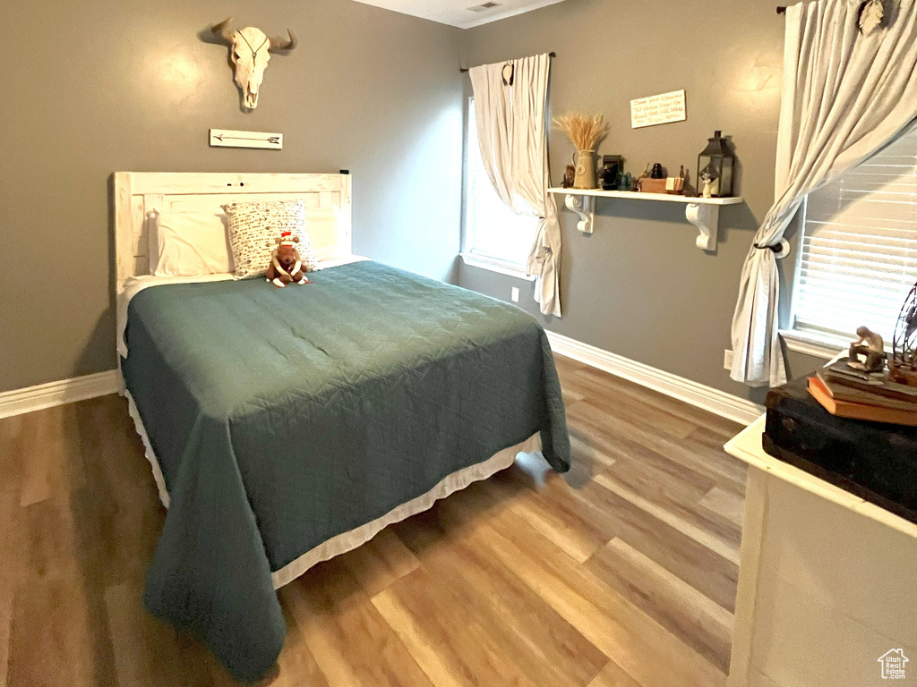 Bedroom with a textured ceiling, wood finished floors, ceiling fan, baseboards, and multiple windows