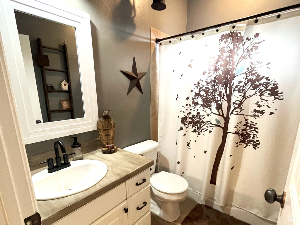Bathroom with tile patterned flooring, vanity, toilet, and curtained shower