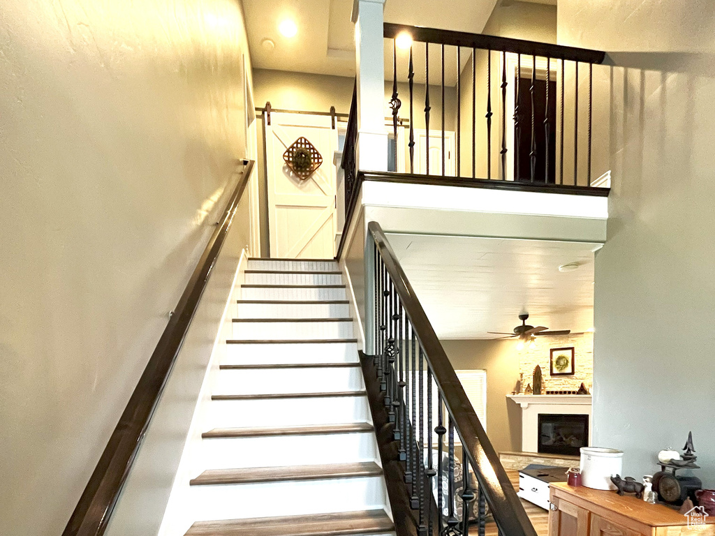 Staircase featuring a fireplace, a ceiling fan, recessed lighting, and wood finished floors
