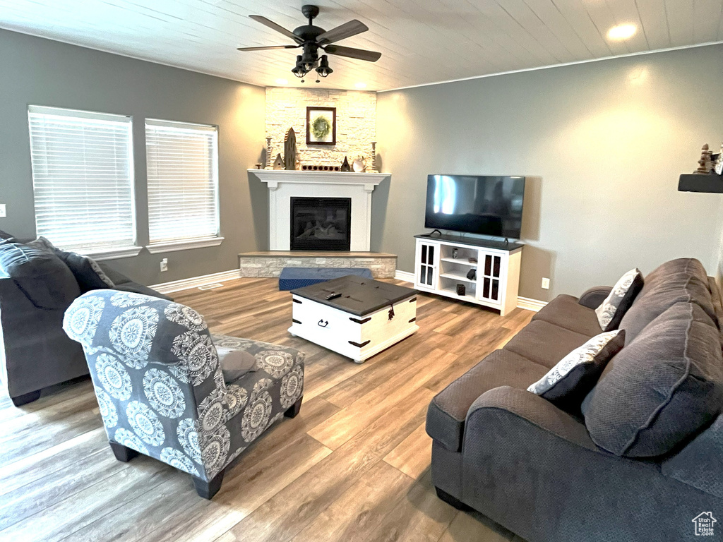 Living area featuring ceiling fan, wood finished floors, a fireplace with raised hearth, and wooden ceiling