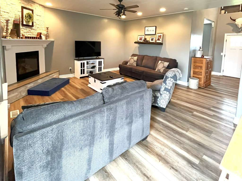 Living area featuring wood finished floors, ceiling fan, a glass covered fireplace, recessed lighting, and baseboards
