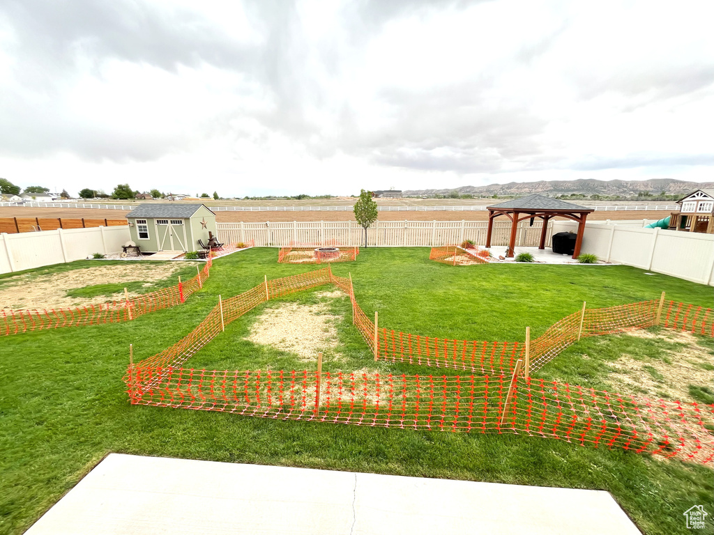 View of yard featuring a gazebo, a storage shed, an outbuilding, and a garden