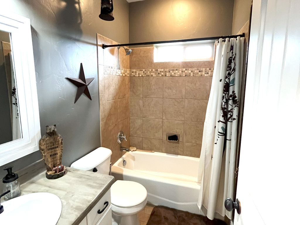 Bathroom with shower / bath combo with shower curtain, vanity, toilet, and tile patterned floors