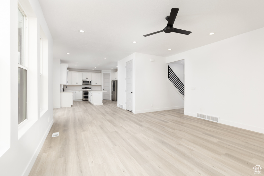 Unfurnished living room with light wood-style floors, ceiling fan, recessed lighting, and baseboards