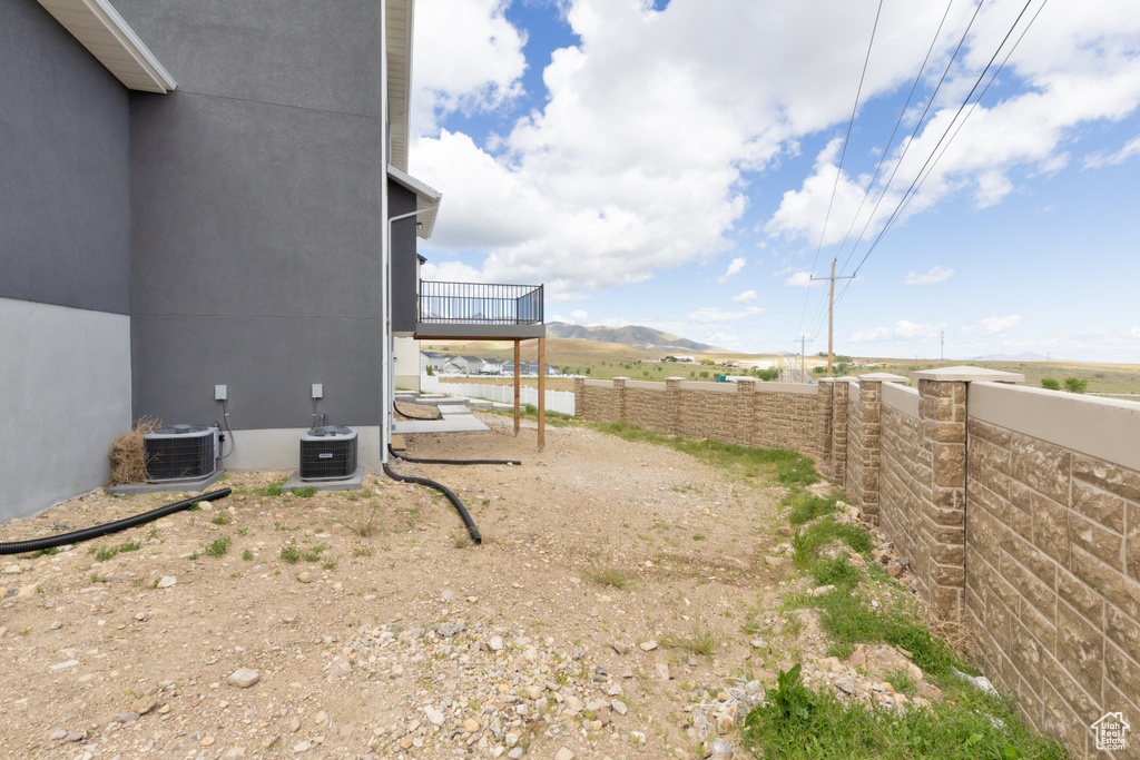 View of side of property featuring a fenced backyard, central AC unit, and a deck with mountain view