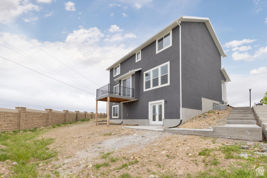 Rear view of property with french doors, stucco siding, fence, and a wooden deck