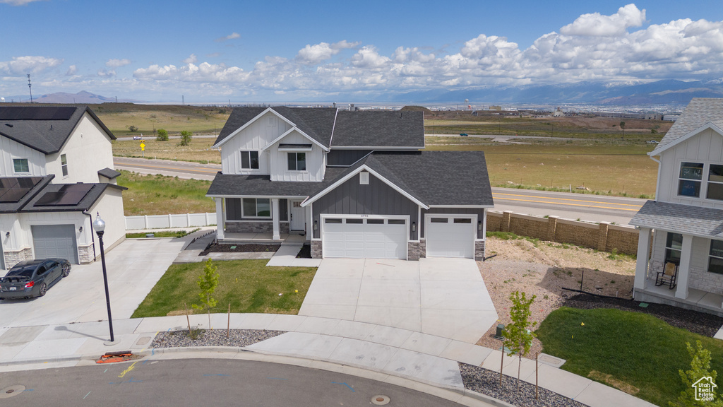 View of front of house with board and batten siding, roof with shingles, concrete driveway, and fence