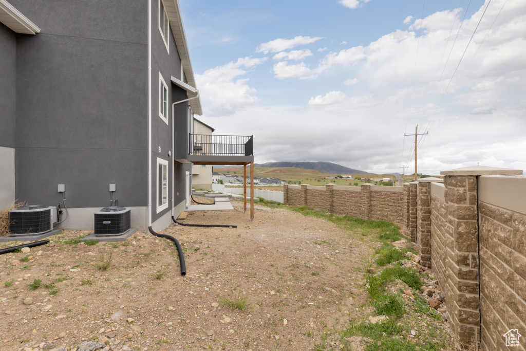 View of yard with central AC, a mountain view, and fence