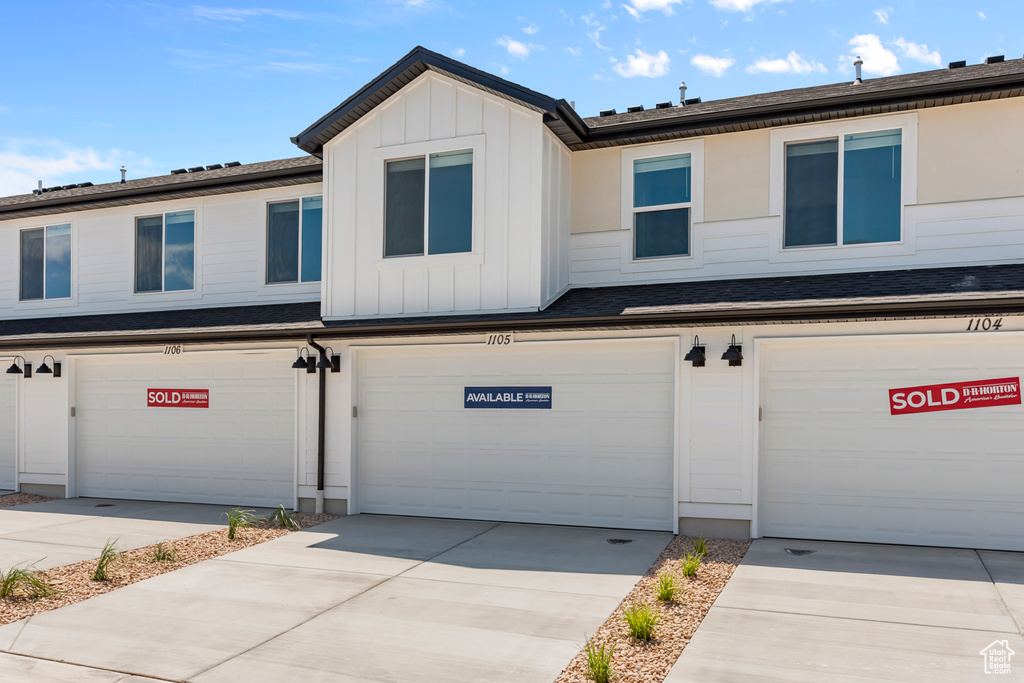 Townhome / multi-family property featuring board and batten siding, an attached garage, and driveway