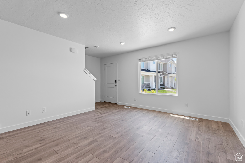 Unfurnished room with a textured ceiling, wood finished floors, baseboards, and recessed lighting