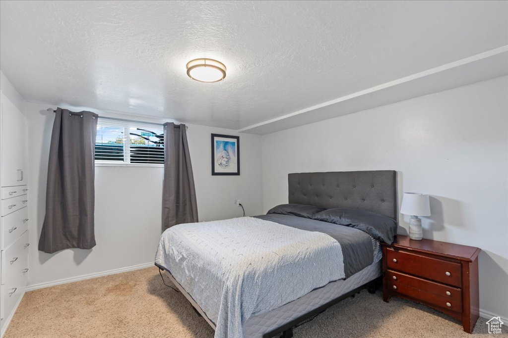 Bedroom with light colored carpet, baseboards, and a textured ceiling