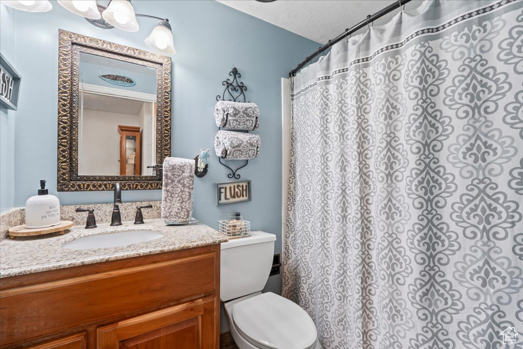Bathroom with toilet, vanity, a shower with curtain, and a textured ceiling