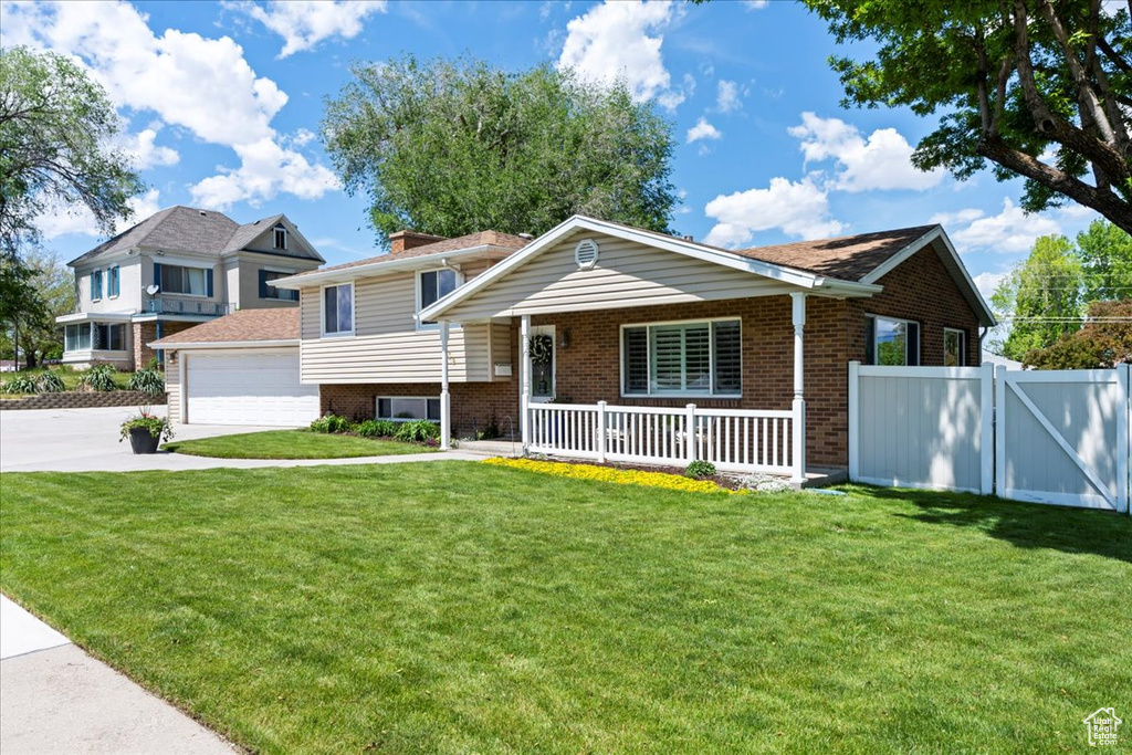 View of front of home featuring brick siding, a porch, driveway, and a garage