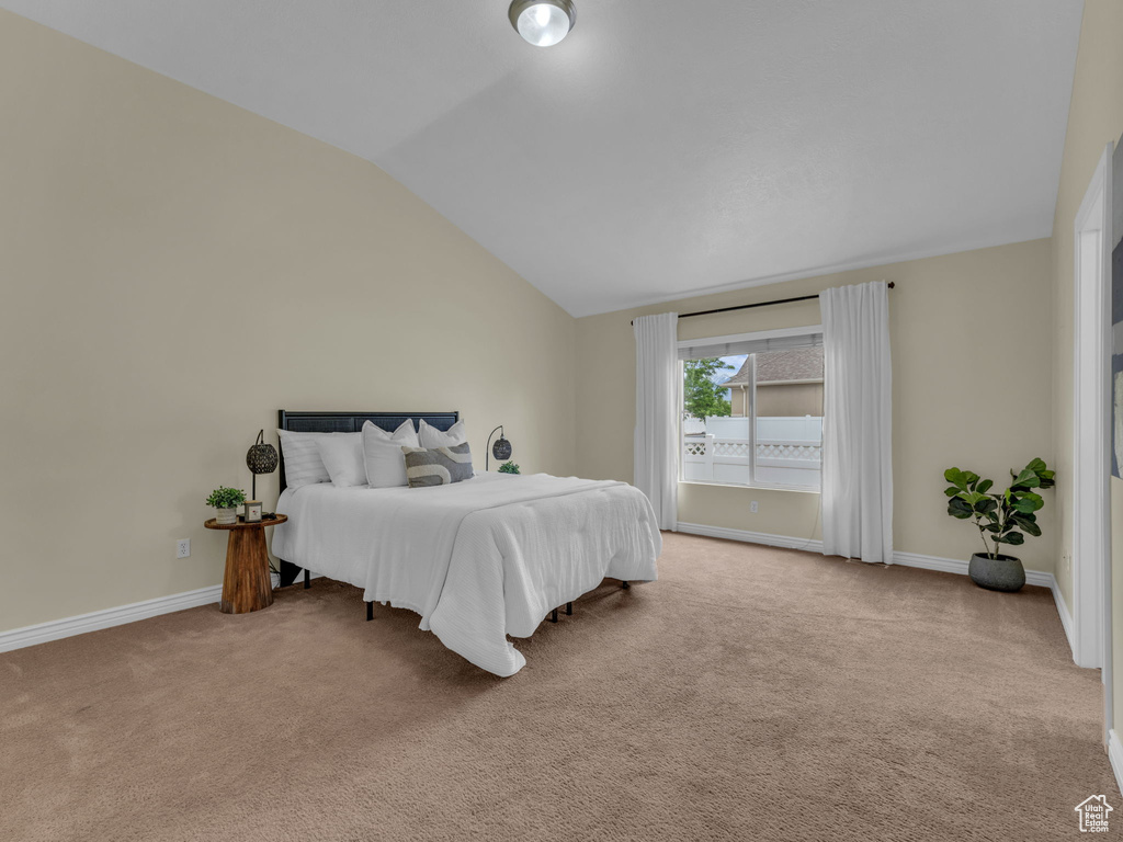 Carpeted bedroom with vaulted ceiling and baseboards