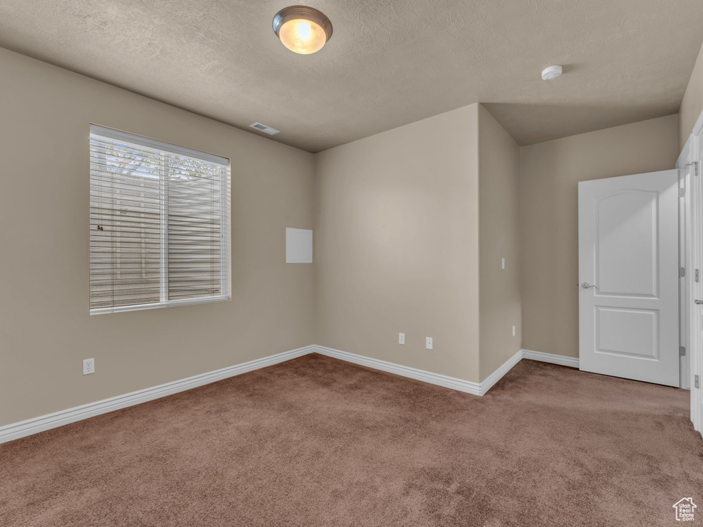 Carpeted empty room with baseboards and a textured ceiling