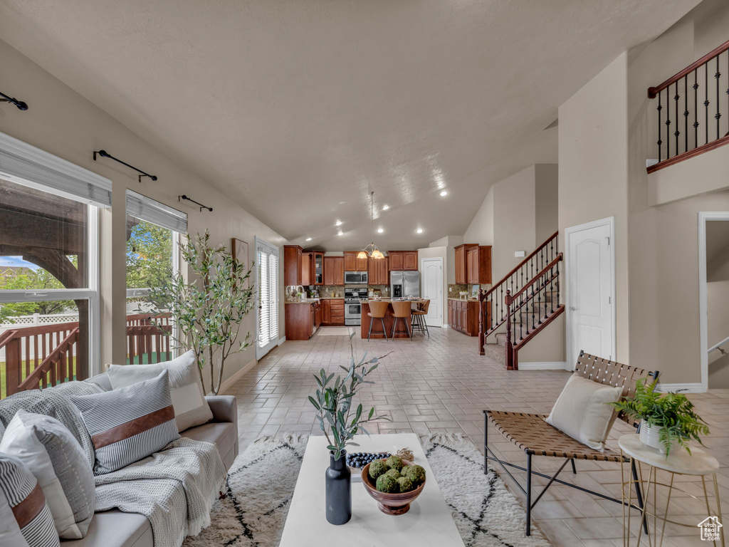 Living area with baseboards, stairs, high vaulted ceiling, and recessed lighting