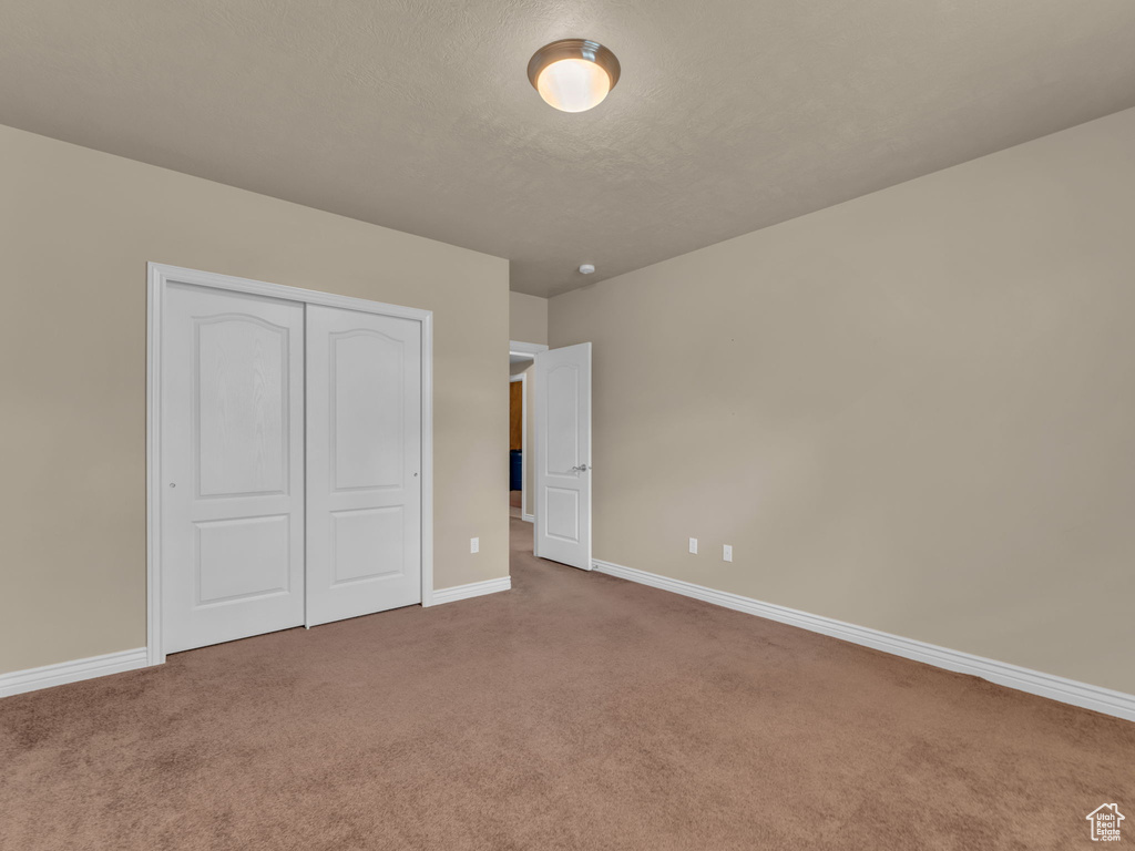Unfurnished bedroom with carpet flooring, baseboards, and a closet