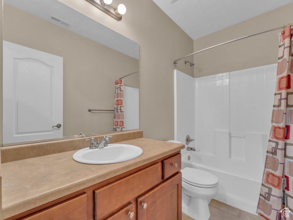 Bathroom with tile patterned flooring, toilet, vanity, and shower / bath combination with curtain