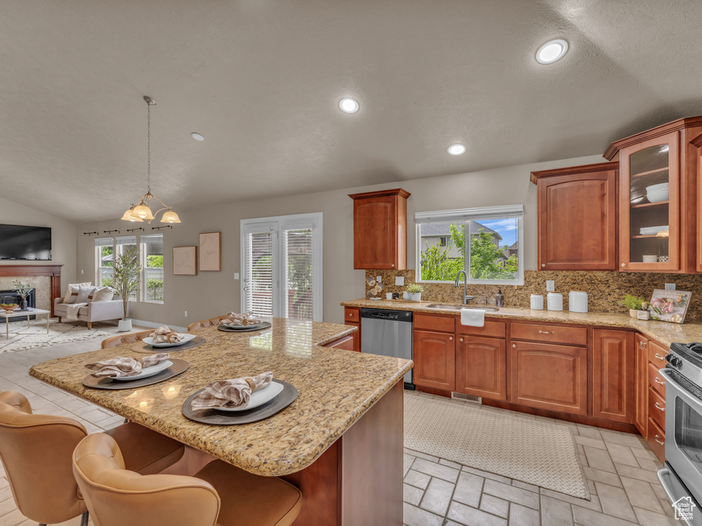 Kitchen featuring appliances with stainless steel finishes, a sink, decorative backsplash, open floor plan, and a chandelier
