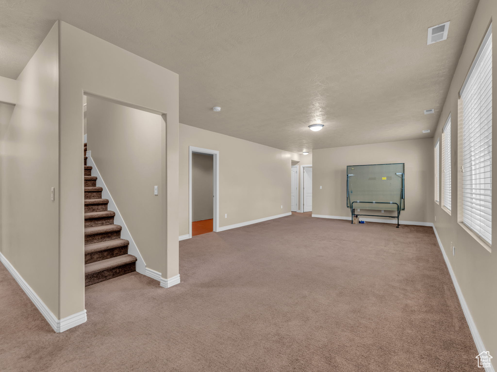 Unfurnished living room with carpet flooring, stairway, and baseboards