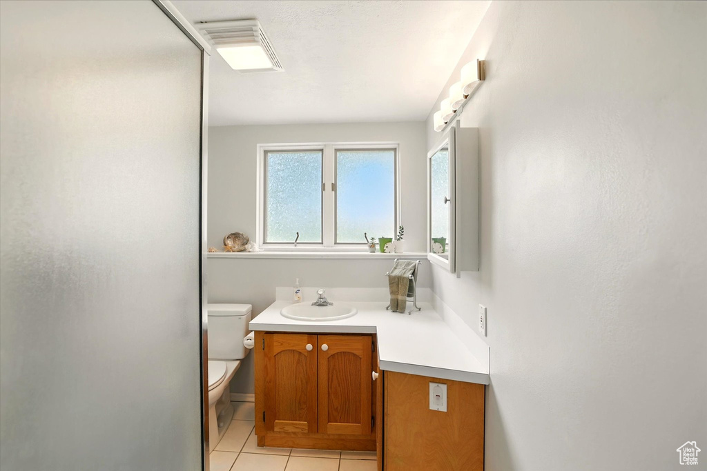 Bathroom with toilet, tile patterned flooring, and vanity