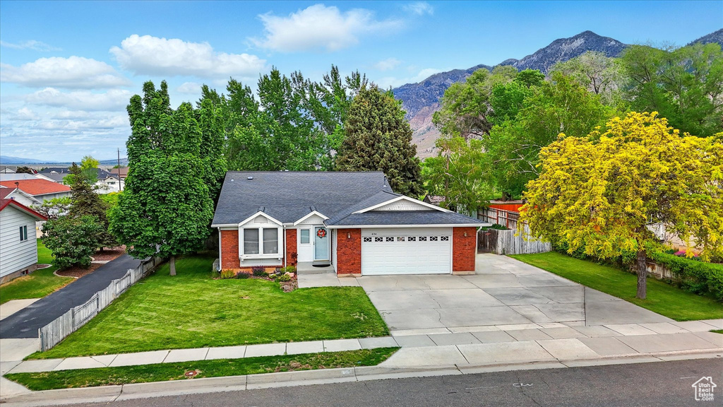 View of front of home with brick siding, a mountain view, concrete driveway, and an attached garage