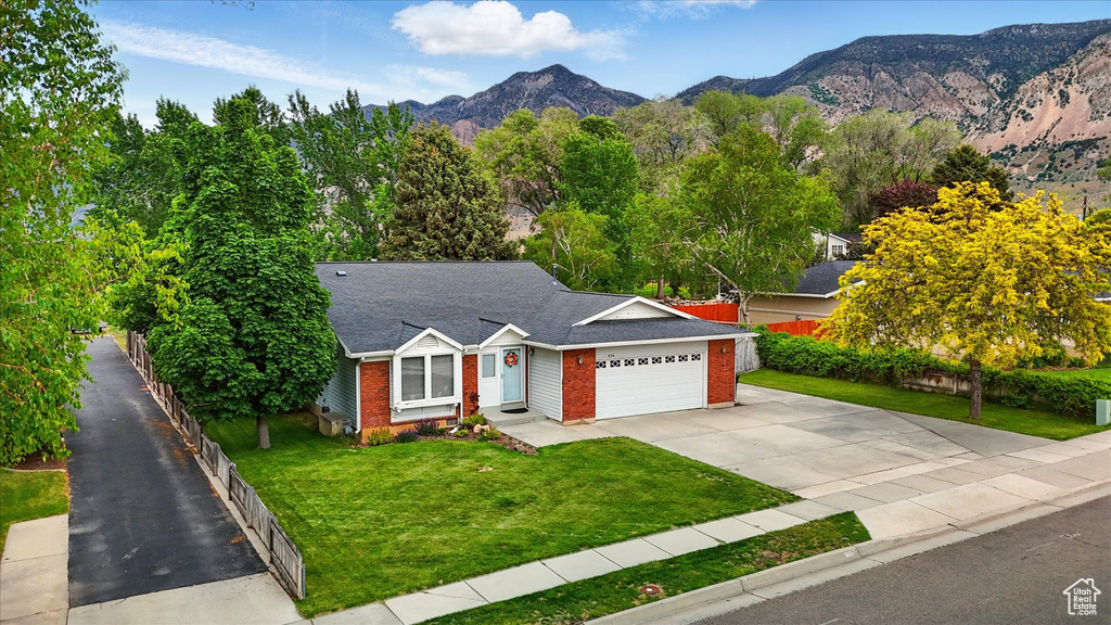 Ranch-style house featuring brick siding, driveway, an attached garage, a mountain view, and a shingled roof