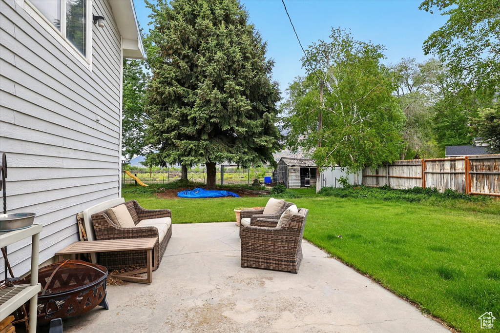 View of patio featuring a fire pit, a storage shed, and an outbuilding