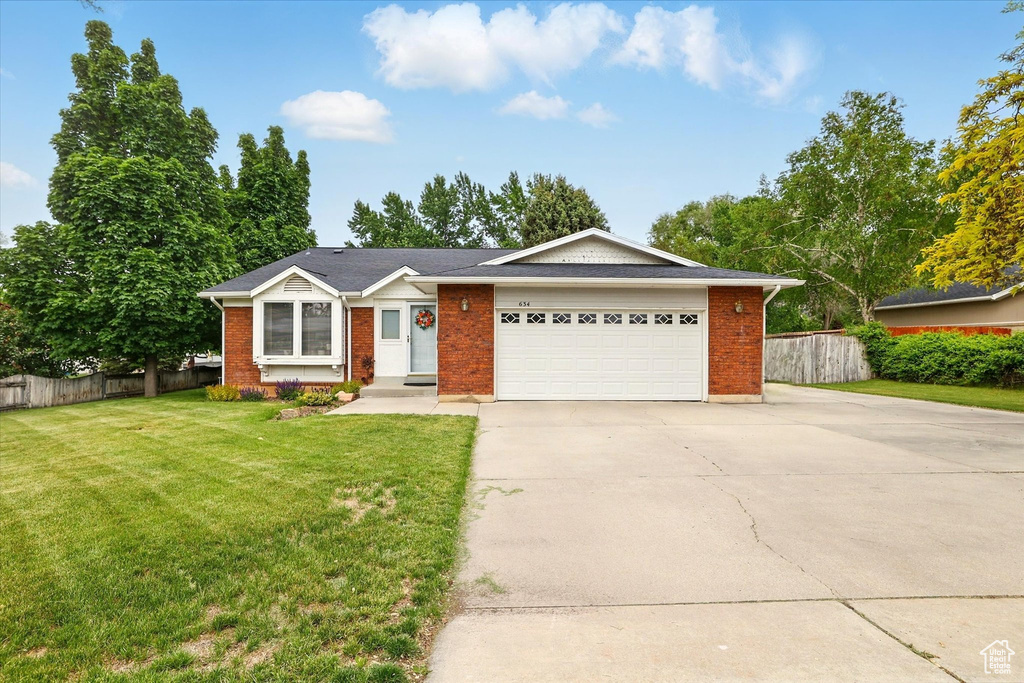 Single story home featuring brick siding, driveway, and a garage