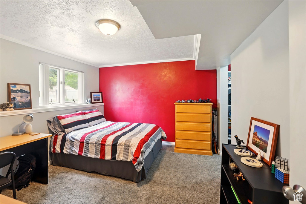 Carpeted bedroom featuring ornamental molding and a textured ceiling