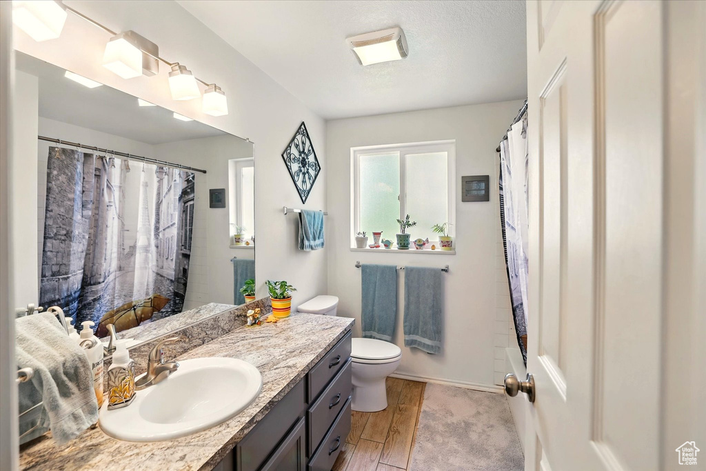 Bathroom with vanity, toilet, wood finished floors, a shower with shower curtain, and baseboards