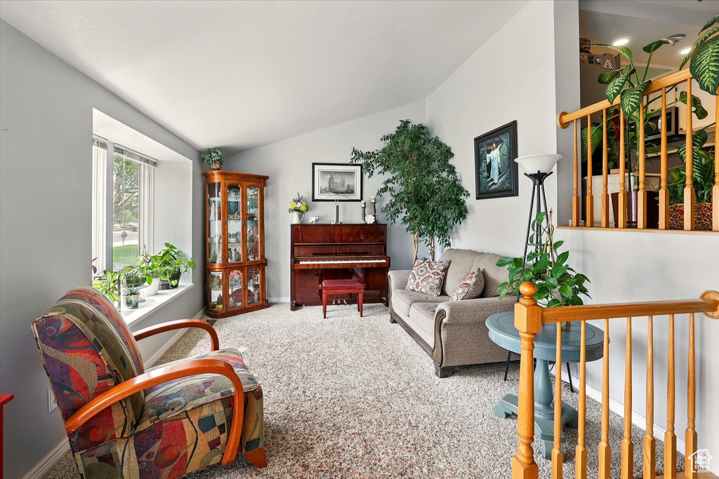 Living area featuring vaulted ceiling, carpet, and baseboards
