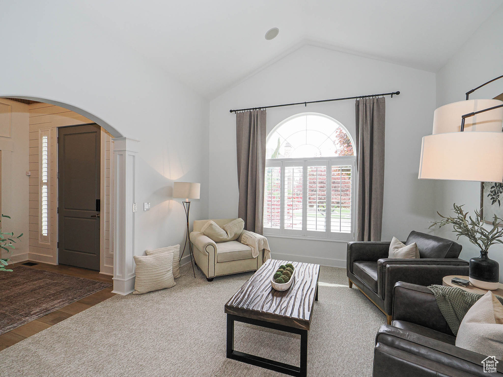 Living room with arched walkways, vaulted ceiling, wood finished floors, and baseboards