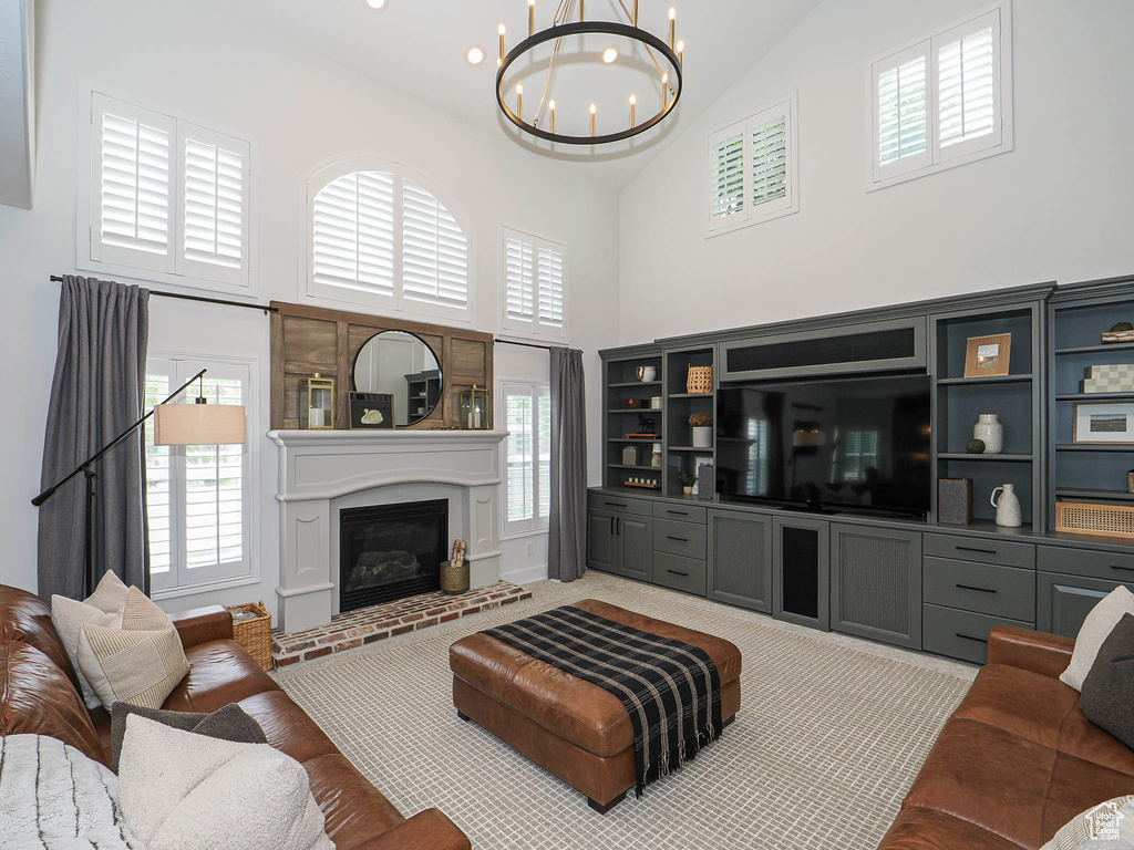 Living room featuring high vaulted ceiling, a chandelier, plenty of natural light, and a fireplace