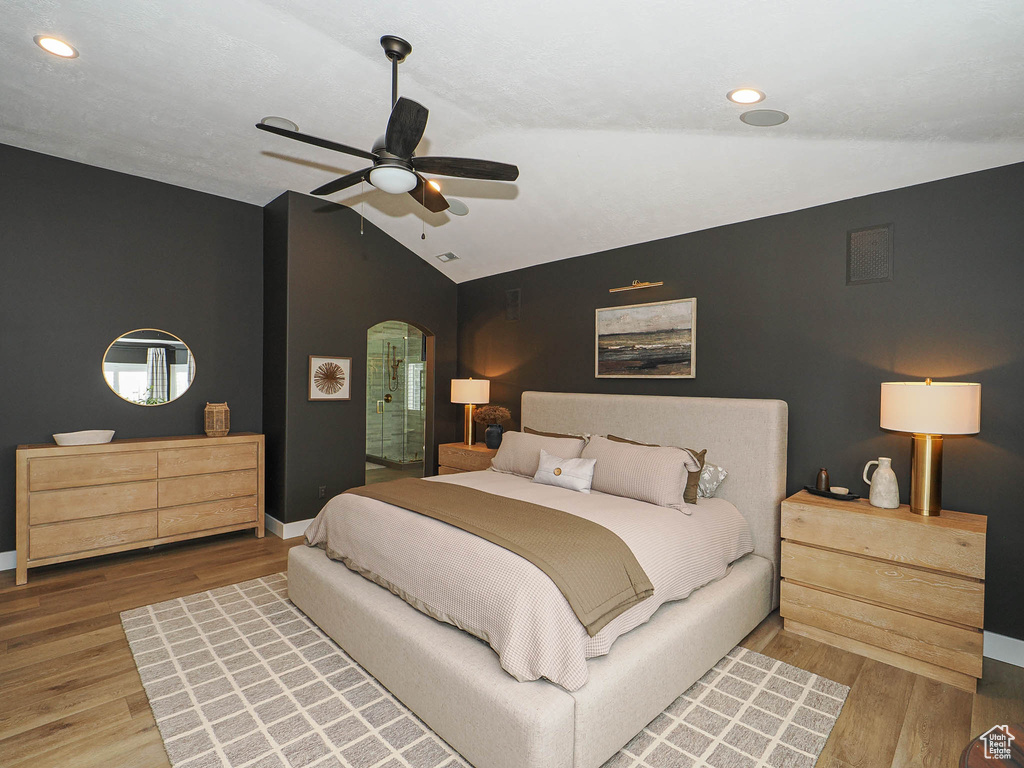 Bedroom featuring arched walkways, lofted ceiling, wood finished floors, baseboards, and recessed lighting