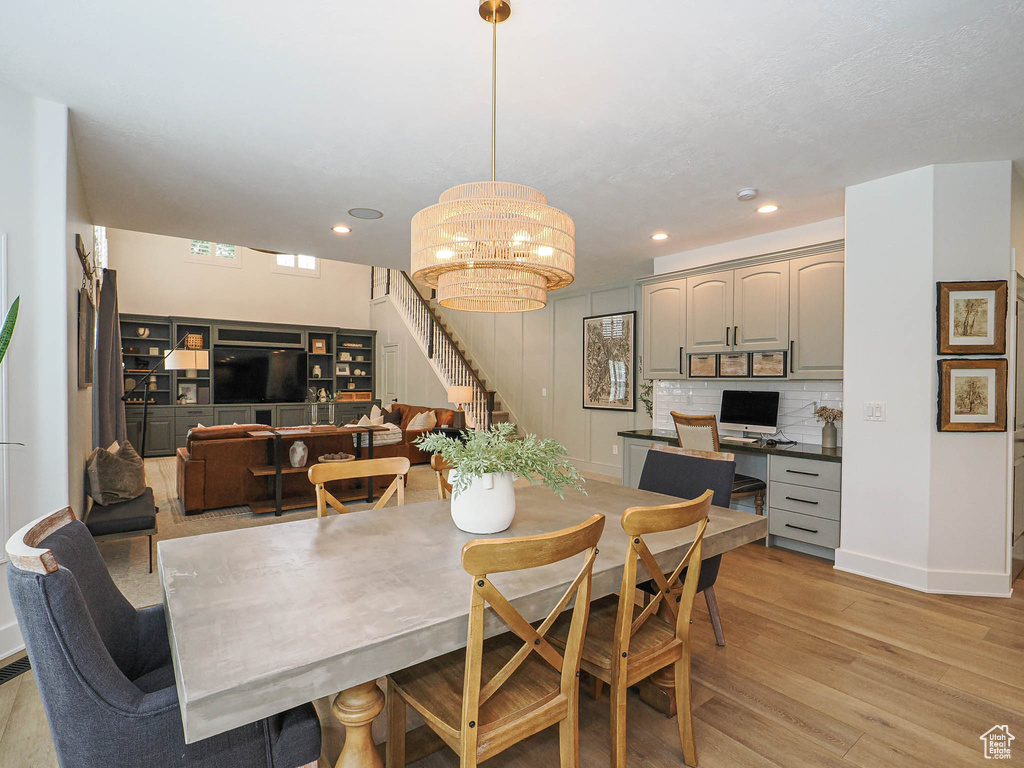 Dining space featuring stairway, light wood-style flooring, a chandelier, baseboards, and recessed lighting