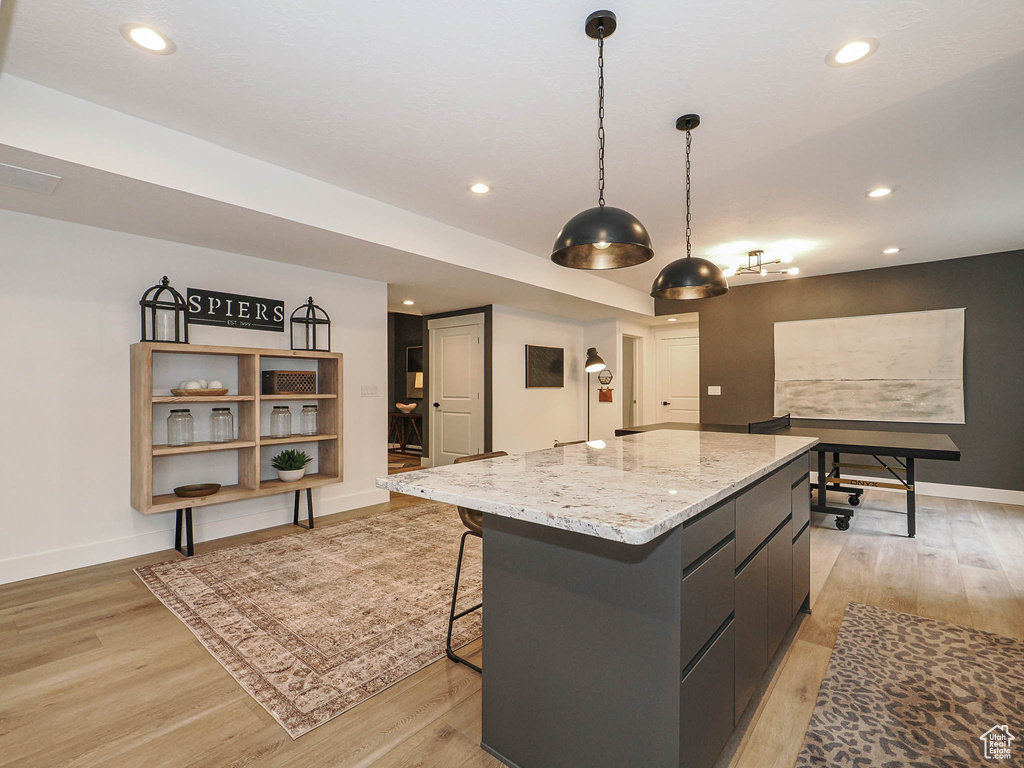 Kitchen featuring a kitchen island, light wood-style flooring, baseboards, recessed lighting, and hanging light fixtures