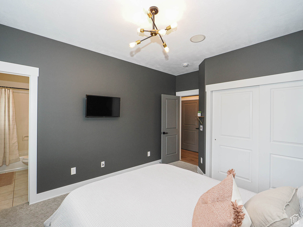 Bedroom featuring a chandelier, a closet, baseboards, light colored carpet, and ensuite bath