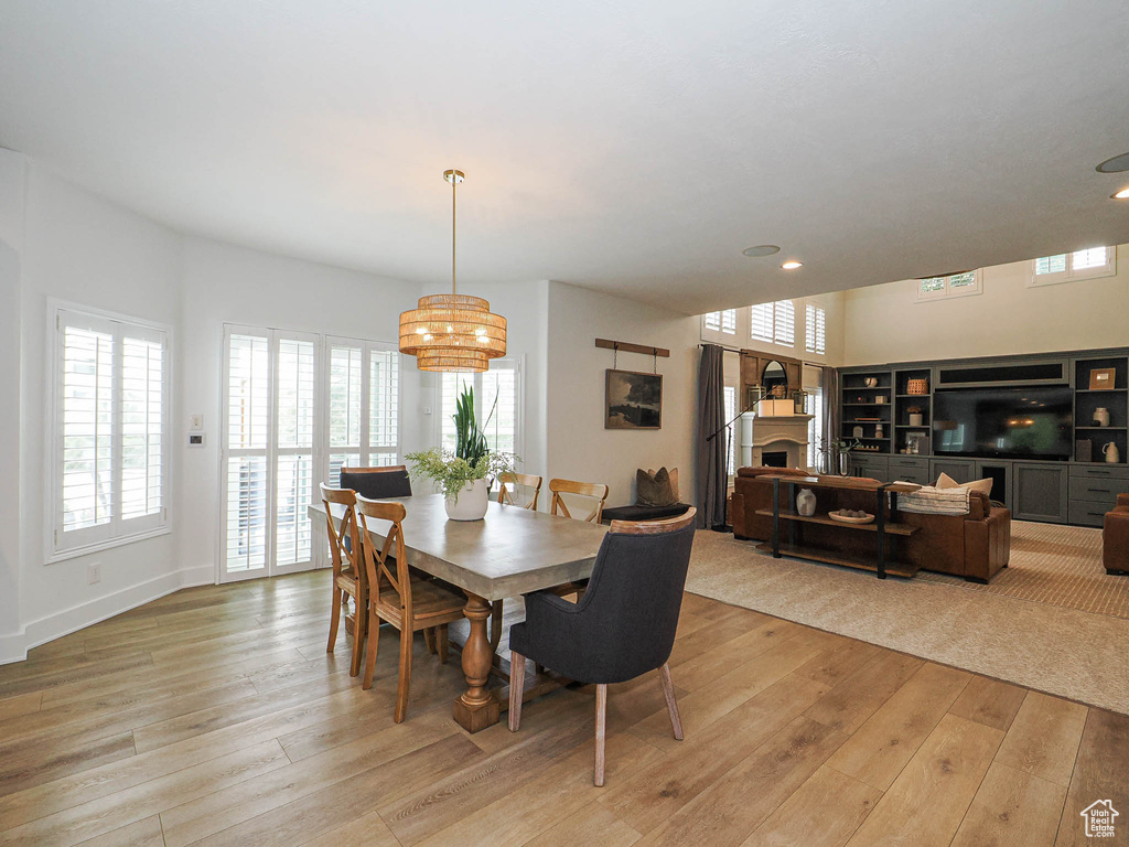Dining room with a fireplace, light wood-style flooring, healthy amount of natural light, and recessed lighting
