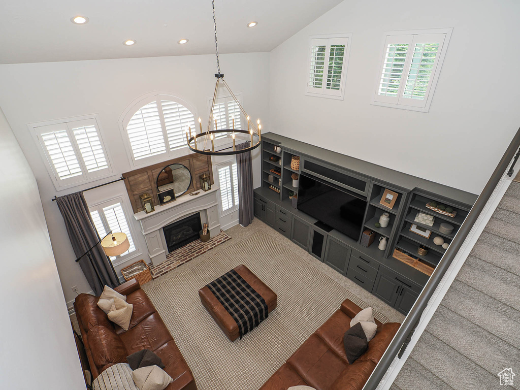 Living room featuring high vaulted ceiling, a chandelier, recessed lighting, healthy amount of natural light, and a glass covered fireplace