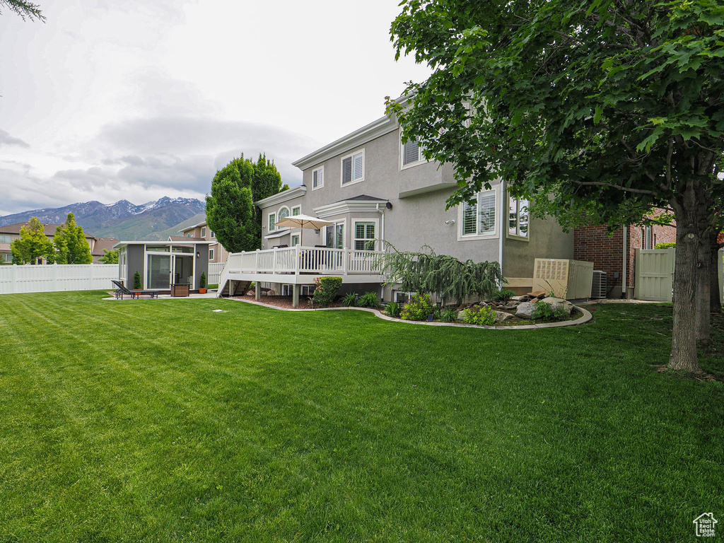 Rear view of house with a sunroom, a deck with mountain view, and stucco siding
