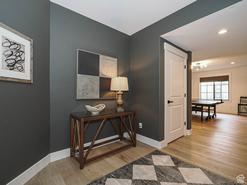 Hallway with wood finished floors, a chandelier, baseboards, and recessed lighting