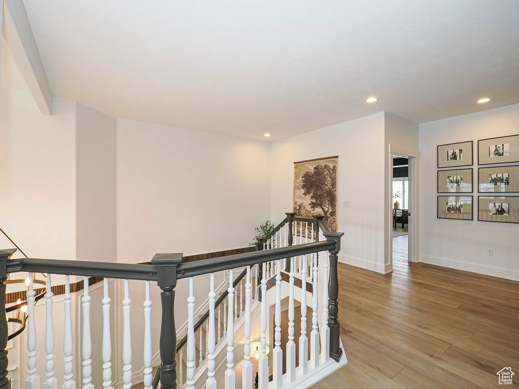 Hallway featuring an upstairs landing, wood finished floors, baseboards, and recessed lighting