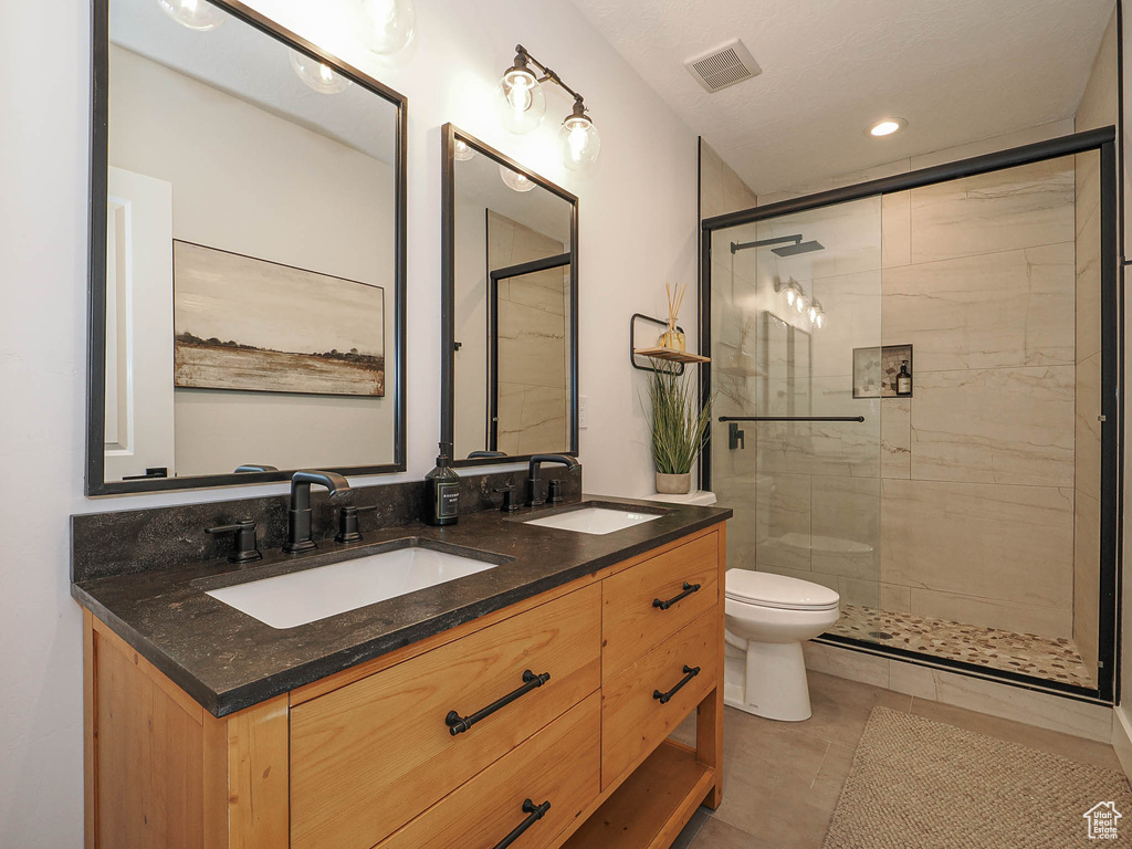 Full bathroom with a stall shower, toilet, double vanity, recessed lighting, and tile patterned floors