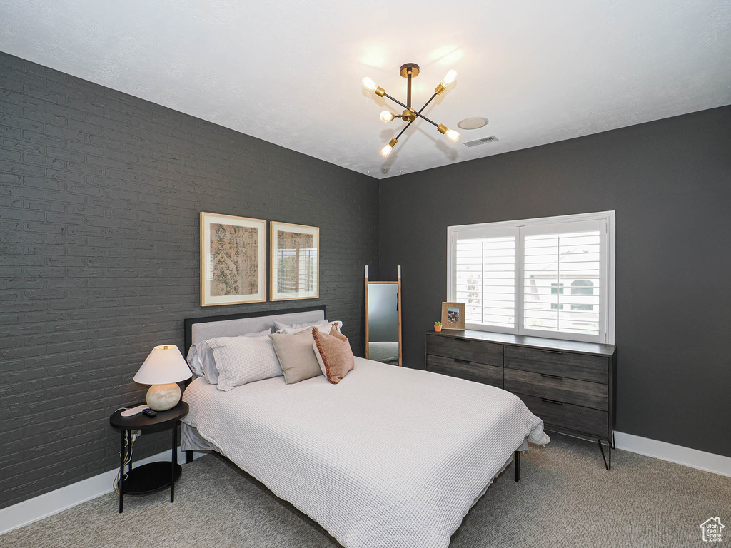 Carpeted bedroom with a chandelier and baseboards