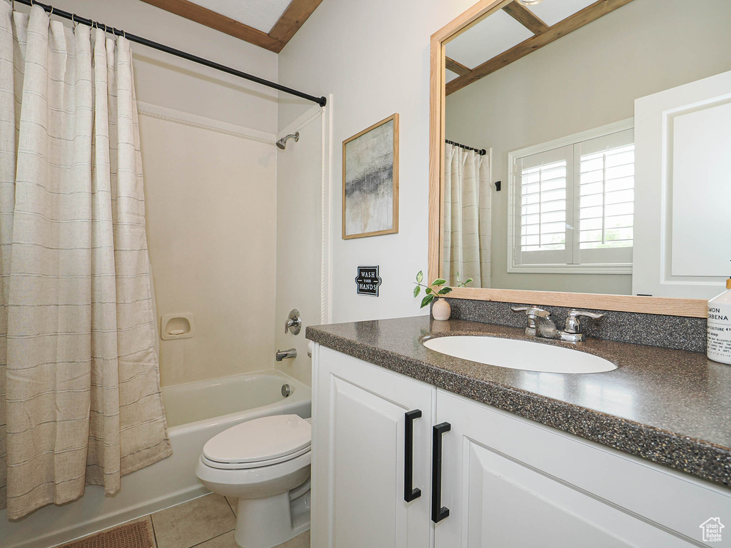 Bathroom with shower / bath combination with curtain, vanity, tile patterned floors, and toilet