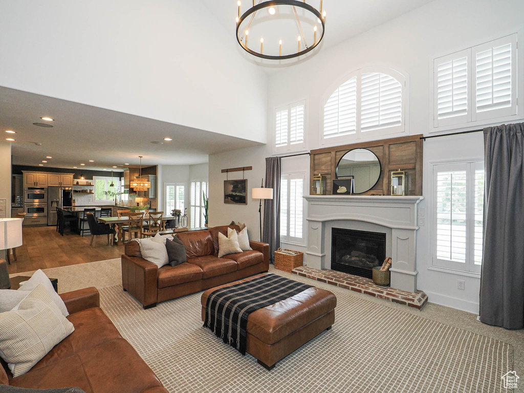 Living room with a chandelier, a glass covered fireplace, recessed lighting, and a towering ceiling
